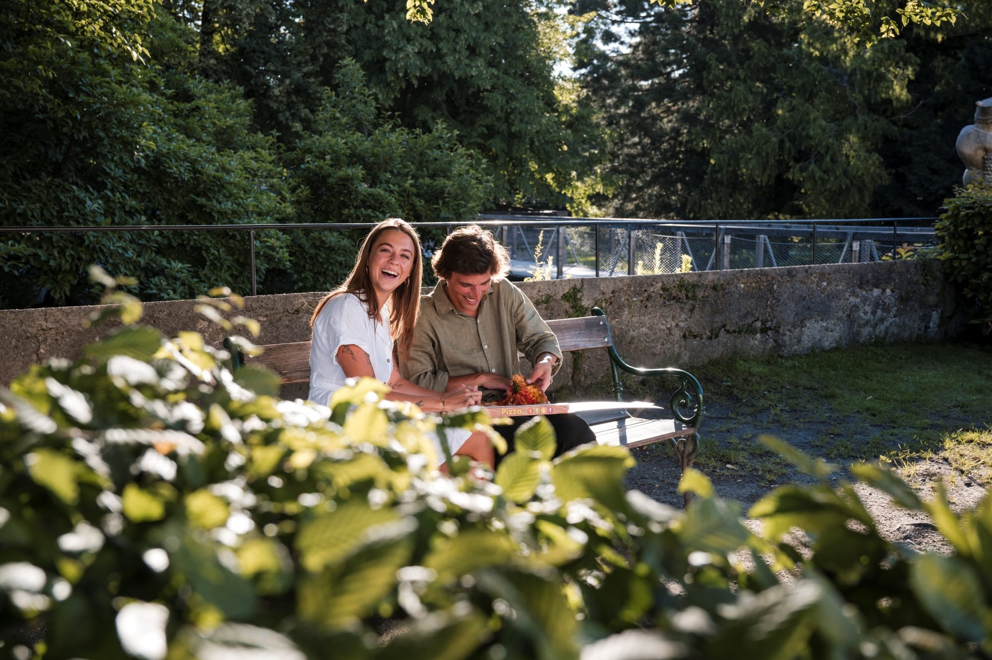 Couple sitting on a bench in a park in Salzburg, surrounded by green nature and a relaxed atmosphere © Lorenz Masser