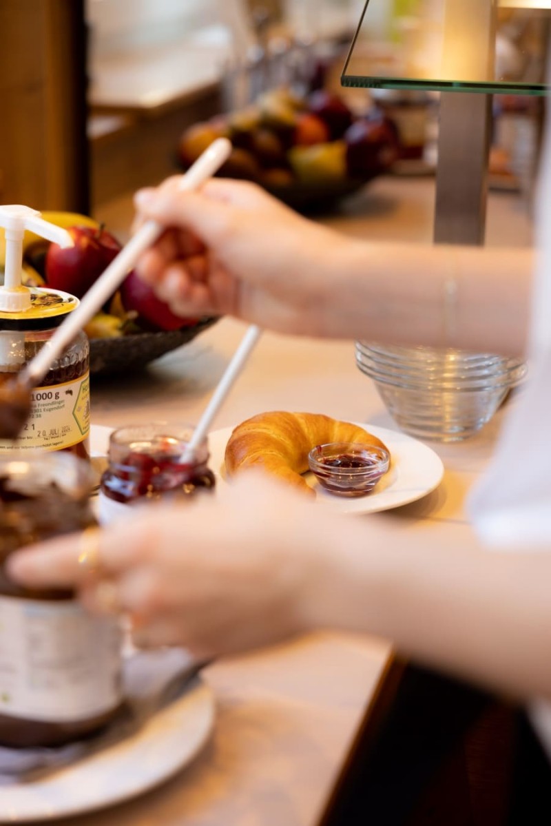 Ein Gast bereitet sein Frühstück im gemütlichen Frühstücksraum des HOTEL max70 zu